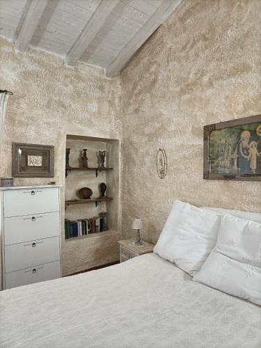 a bedroom with a white bed with a dresser and shelves at Funtana e Caddos apartment in Berchidda