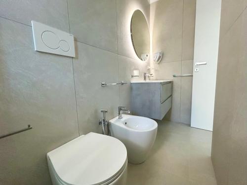 a white bathroom with a toilet and a sink at Sea Apartment - Torre Pali in Torre Pali