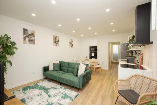 a living room with a green couch and a kitchen at City Garden House by Hosty in Sacavém