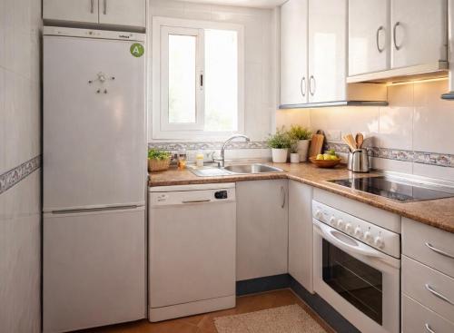 a white kitchen with a sink and a refrigerator at Cala Rajá 5 in La Isleta del Moro