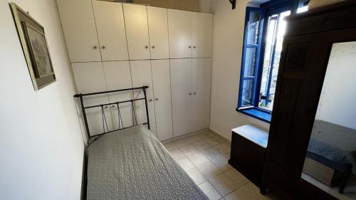 a small bedroom with a bed and a window at Camaraki Capitano House , Chora Serifos in Serifos Chora