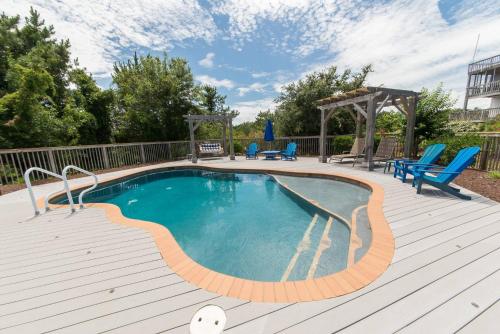 a swimming pool on a wooden deck with blue chairs at Just For Fun - Duck, Schooner Ridge, Pool Open 4/15, Pool Heat Option, Hot Tub, Close to Downtown in Duck