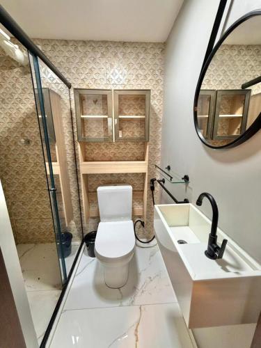 a bathroom with a toilet and a sink and a mirror at Estilo e Praticidade - Seu Flat ao lado do mar in São Luís