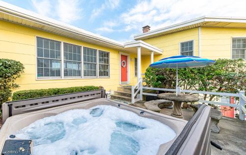 a hot tub in front of a house with an umbrella at Gypsea Rose - Southern Shores, Oceanfront, Ocean View, Hot Tub, Pets OK, Flex Stays in Southern Shores