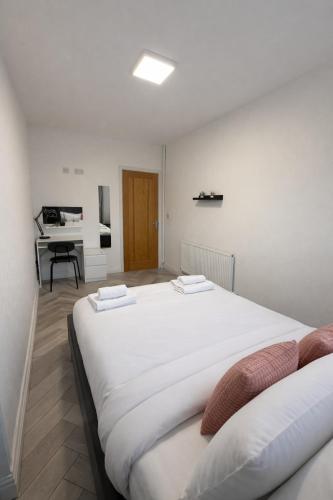 a bedroom with a large white bed and a piano at Modern Comfort for Longer Stays in Bury, 2-Bedrooms in Walmersley
