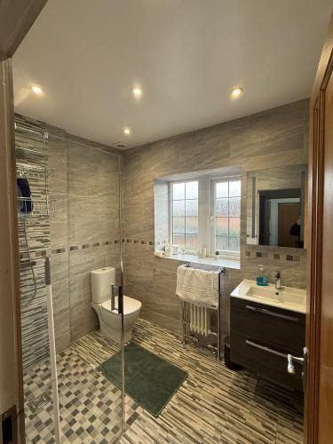 a bathroom with a shower and a toilet and a sink at Modern Comfort for Longer Stays in Bury, 2-Bedrooms in Walmersley