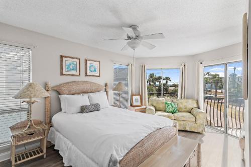 a bedroom with a bed and a chair and windows at Sea-Esta in Destin