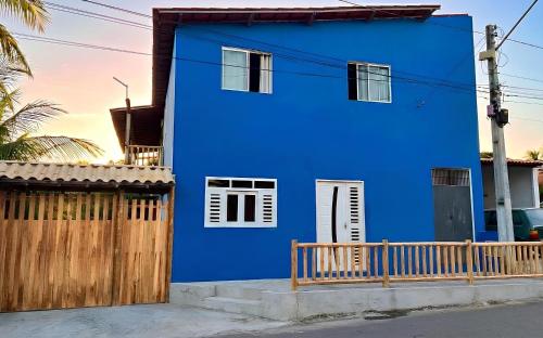 a blue house with a wooden fence in front of it at Suites Fernandes Fortim in Fortim