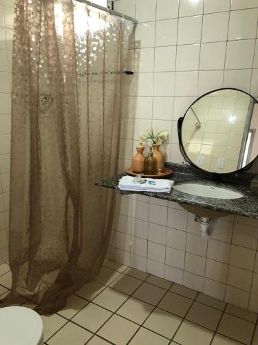 a bathroom with a shower curtain and a sink at Barrah flat in Barra de São Miguel