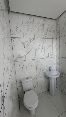 a white bathroom with a toilet and a sink at Cantinho dos Pássaros Centro Penedo RJ in Penedo