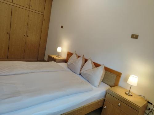 a bedroom with a large white bed with two lamps at Bergblick 33 in Plaus