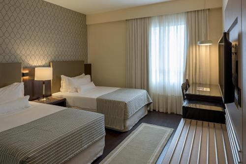a hotel room with two beds and a window at Bourbon Hotel & Suites Curitiba in Curitiba