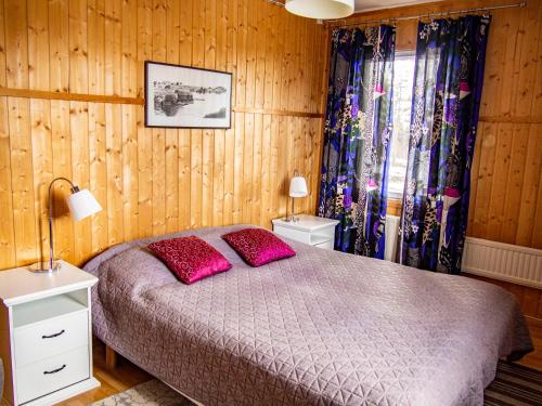a bedroom with a bed with pink pillows and wooden walls at Kätkävaara Wilderness Lodge in Muurola