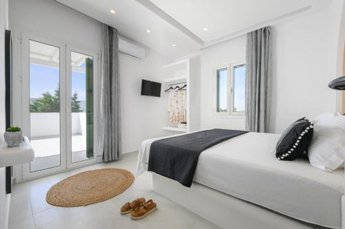 a white bedroom with a bed and a large window at Anemomylos in Kastraki