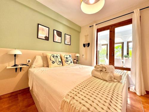 a bedroom with a large white bed with a window at La Palmera Suite Calpe in Calpe