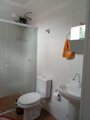 a white bathroom with a toilet and a sink at Kitnet Imigrantes in Holambra