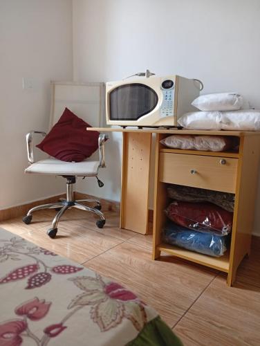 a desk with a computer and a chair in a room at Kitnet Imigrantes in Holambra