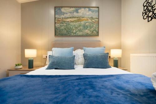 a bedroom with a large bed with blue pillows at Silverdale Lodge, HotTub, Wi-FI, Quiet & Sleeps 4 in Warton