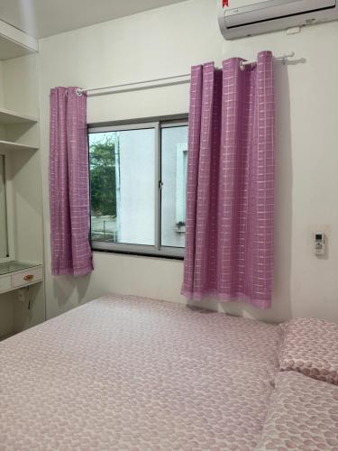 a bedroom with purple curtains and a bed and a window at Diamond Summer in Caucaia