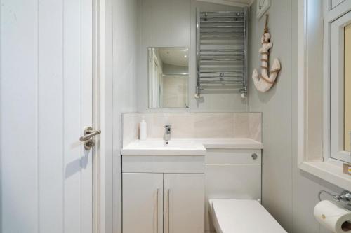 a white bathroom with a sink and a mirror at Silverdale Lodge, HotTub, Wi-FI, Quiet & Sleeps 4 in Warton