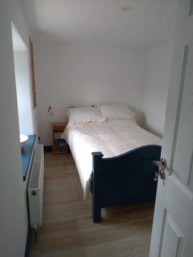 a small bedroom with a bed with white sheets at Carrowkeel Cottage in Athlone