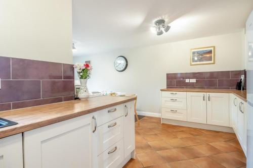 a kitchen with white cabinets and a clock on the wall at 3 Bed in Little Walsingham oc-1229 in Little Walsingham