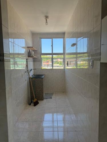 a tiled bathroom with a shower and a window at Apê 250m da Orla de Piúma in Piúma