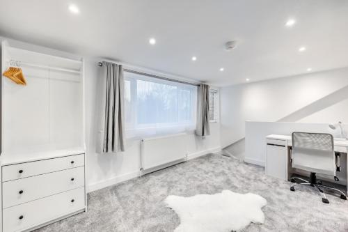 a white bedroom with a desk and a window at 4 Bedroom 4 Bathroom House - Sleeps 7 - Prime Location, Free Parking, Self-Check-In, Workspace, Fast Wifi and Smart TV with Virgin TV and Netflix by Yoko Property in Northampton