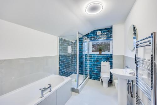 a bathroom with a tub and a toilet and a sink at 4 Bedroom 4 Bathroom House - Sleeps 7 - Prime Location, Free Parking, Self-Check-In, Workspace, Fast Wifi and Smart TV with Virgin TV and Netflix by Yoko Property in Northampton