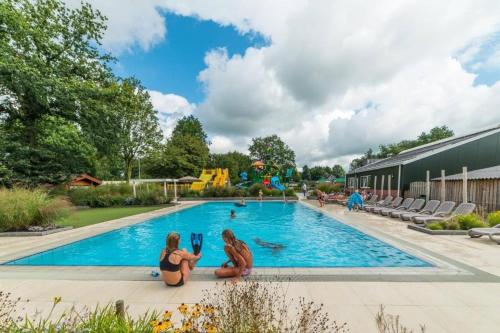 two girls are sitting next to a swimming pool at Sola Lodge - Luxe chalet voor het hele gezin in Mariënberg