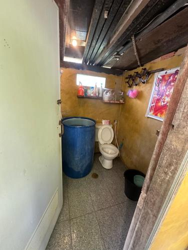 a bathroom with a toilet and a large blue barrel at Tan Homestay in Ko Lanta