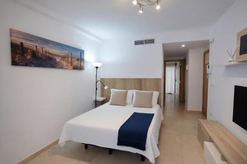 a bedroom with a white bed and a tv at Benidorm Center Playa Poniente in Benidorm