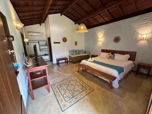a bedroom with a bed and a living room at Vila Sol Chalés in Pôrto de Pedras