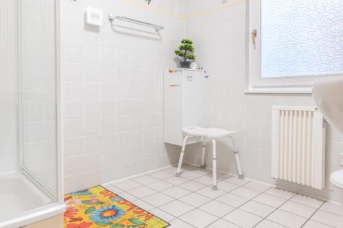 a white bathroom with a shower and a stool at Kellerwald in Frankenau