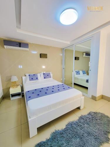 a bedroom with a large white bed and a mirror at Appart M'Rode Baguida in Lomé