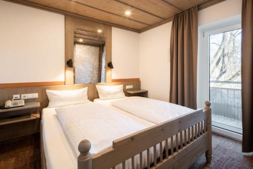a bedroom with a large bed and a window at Hotel Promenade in Bad Füssing