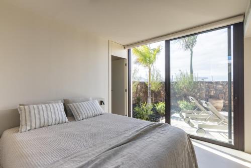 a bedroom with a bed and a large window at Gara Suite Boutique Design Villa Private Pool in Lajares