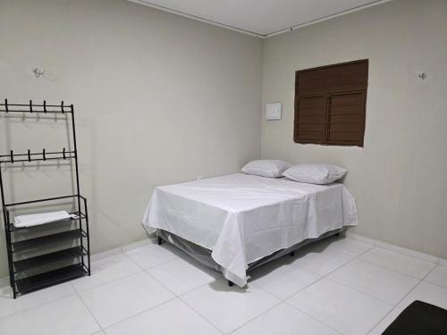 a bedroom with a bed with white sheets and a window at Hotel Fazenda Arena Green in Cajazeiras