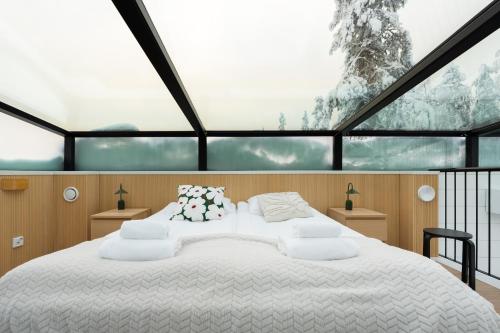 a large white bed in a room with a large window at Levin Primus - Your Glass-Roof Gateway to Laplands Magic in Levi