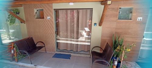 a porch with two chairs and a glass door at Aconchego da Jandaia in Imbassai