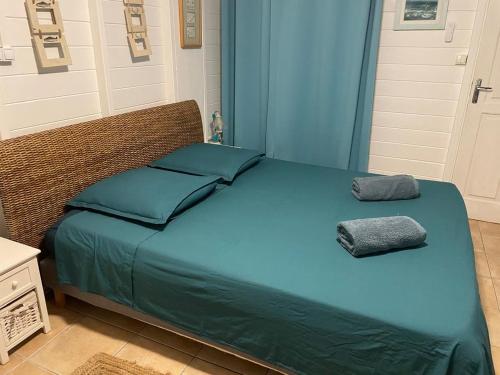 a bed with blue sheets and two pillows on it at Casefilo in Sainte-Luce