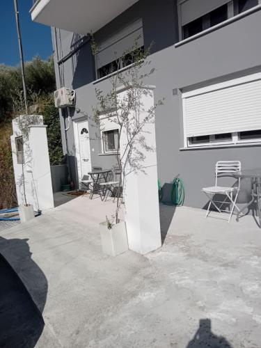 a white house with chairs and a plant on a patio at Eva's apartments in Nafpaktos