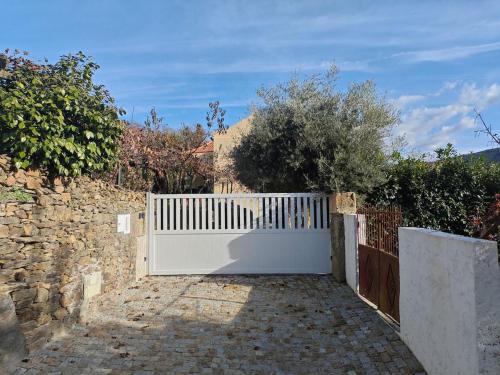 a white fence in front of a stone wall at EiraDouro - Casa Oliveira in Mós