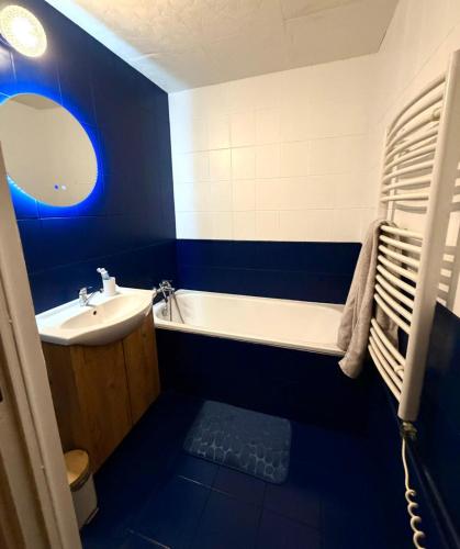 a blue bathroom with a sink and a bath tub at Aldrovské Trio in Vítkovice