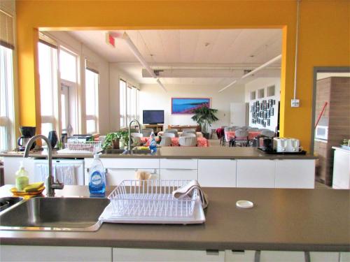 a kitchen with a sink and a large mirror at Auberge La Petite École de Forillon in Gaspé