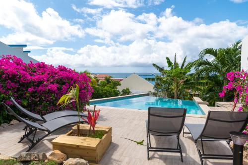 a patio with a swimming pool and pink flowers at Blue Sail Rooms in Koolbaai