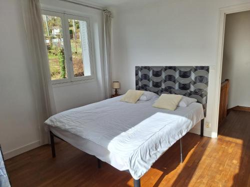 a large bed in a room with a window at Le Jardin d'Elise - Maison 10 personnes avec jardin - proche centre ville in Brive-la-Gaillarde