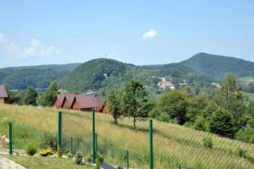 a fence in a field with mountains in the background at Domki Piękny Widok u Karola in Solina