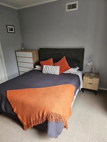 a bedroom with a large bed with an orange blanket at Little Hill on Sycamore in New Plymouth