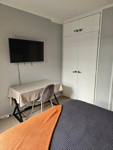 a bedroom with a table and a tv on a wall at Little Hill on Sycamore in New Plymouth